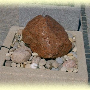 Roter       Granit- Quellstein auf beigem Zierkies in Livorno-Becken (Größe  80/80/35       cm)